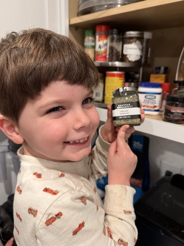 Young Boy Helping in Kitchen with Organic Rosemary