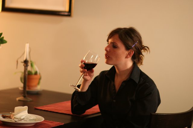 Woman Savoring Red Wine at Dinner Table