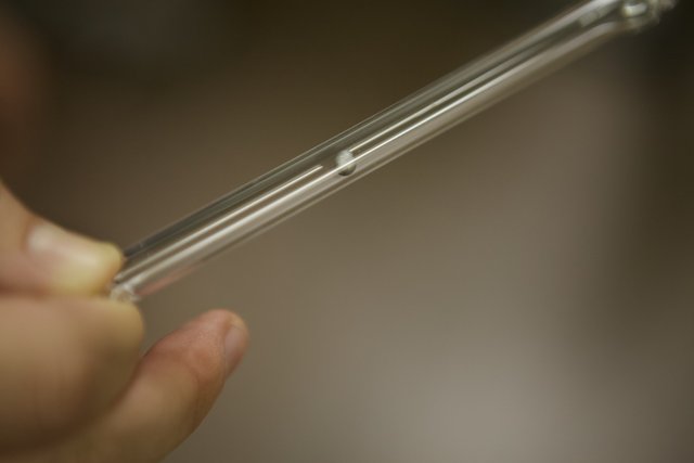 A person holding a clear tube with metal piece