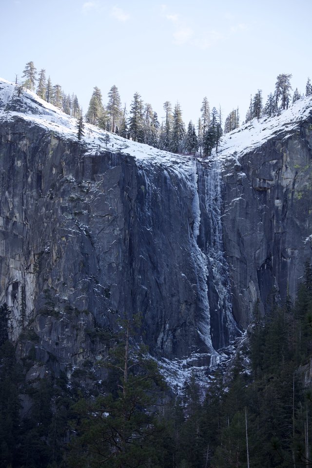 Frozen Waterfall on Snow-Covered Granite Cliff Face