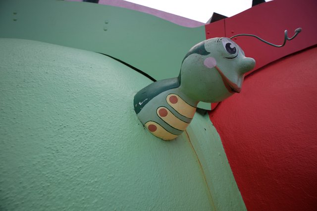 Whimsical Green Caterpillar Sculpture on Colorful Wall