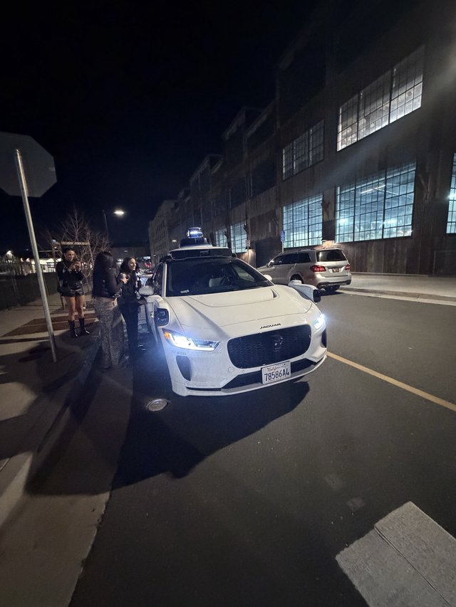 Autonomous Jaguar I-PACE at Night with Onlookers