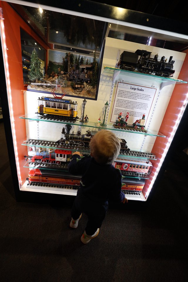 Child Explores Vintage Train Models at Museum Display