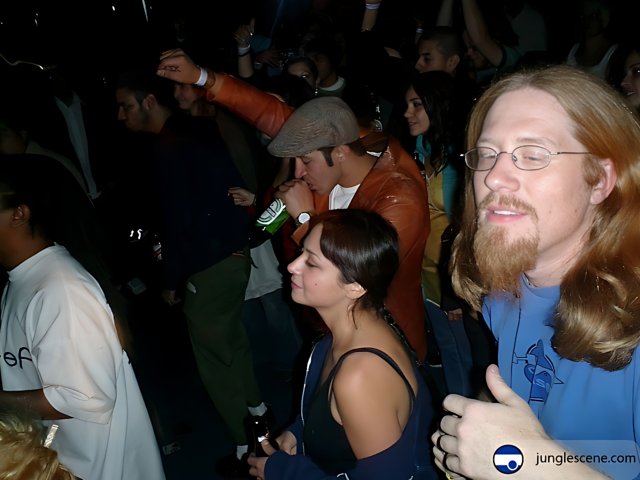 Man with Long Hair and Glasses Stands before Excited Crowd
