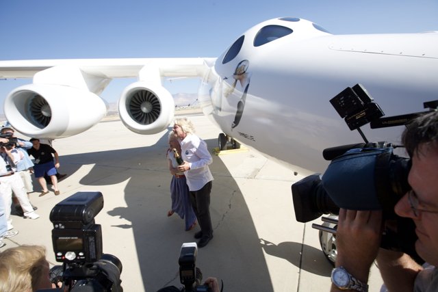 Sky High Snap Caption: A man captures the sleek lines of an aircraft soaring through a bright blue sky.