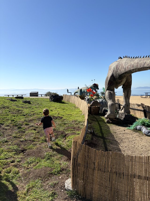 Child Encounters Giant Dinosaur at Beachside Park
