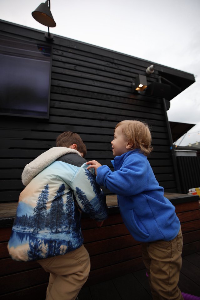 Two Children in Blue Coats at Outdoor Venue