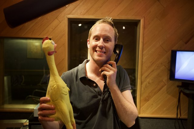 Man and Chicken Toy at the Microphone