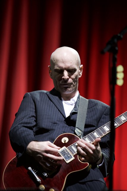 Bald Man in Suit Rocks Out on Electric Guitar