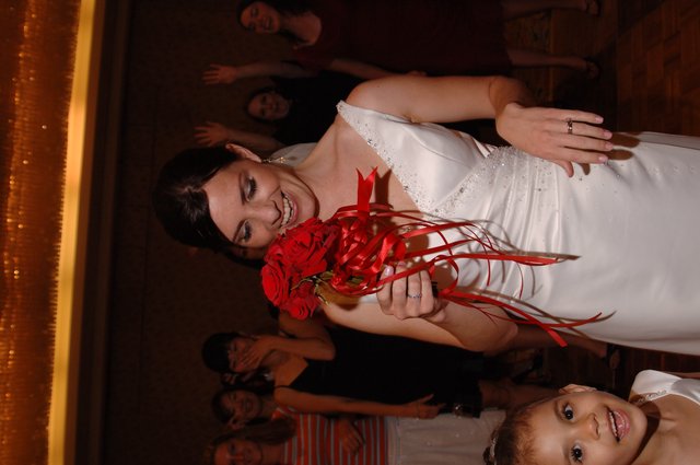 Bride Laughs While Clutching Red Rose Bouquet