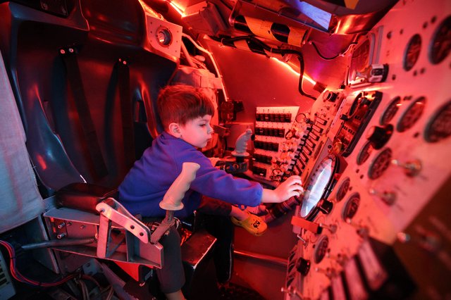 Young Astronaut Explores Space Capsule Interior at Museum