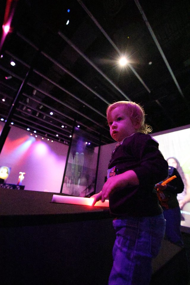 Toddler Mesmerized by Interactive Museum Exhibit at Night