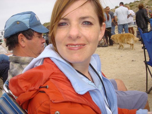 Woman Smiling at Sandy Outdoor Gathering Near Coast