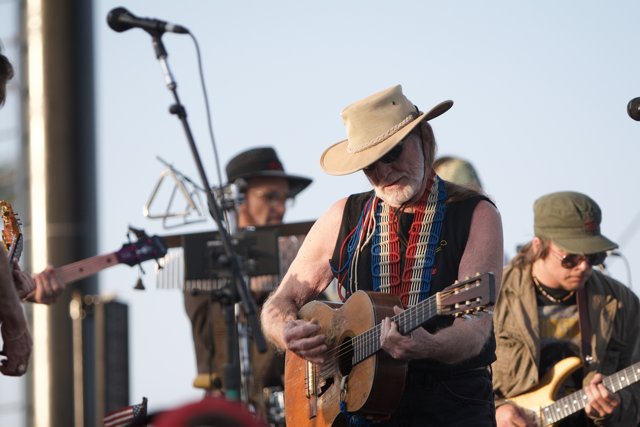 Willie Nelson strums his guitar and sings to the skies