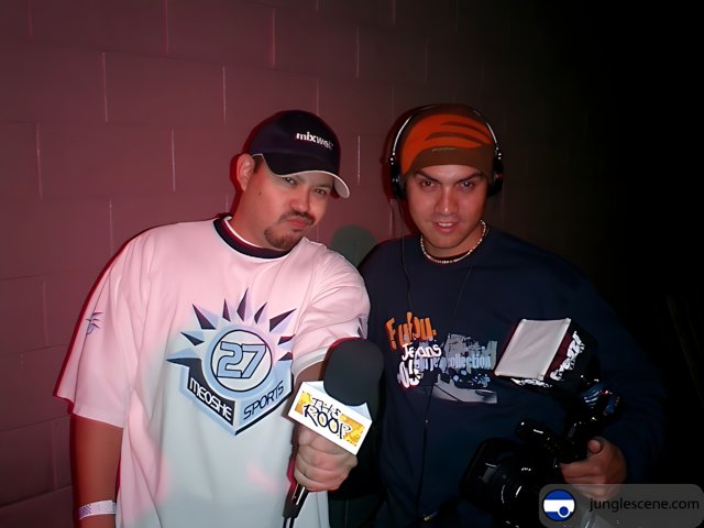 Two Men Holding Microphones and a Baseball Cap