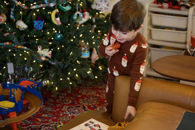 Young Child Opening Christmas Present by Decorated Tree