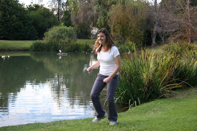 Woman Dancing Joyfully by a Tranquil Park Pond