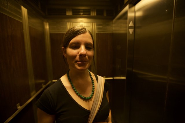 Serene Woman in Golden-Lit Vintage Elevator