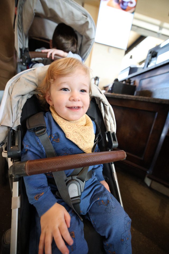 Smiling Toddler in Double Stroller at Restaurant