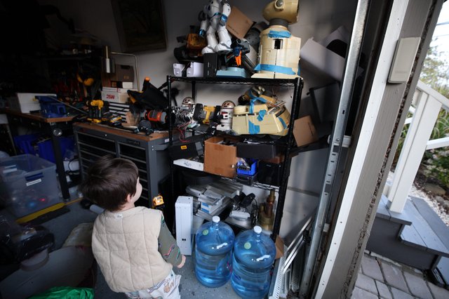 Young Child Exploring Cluttered Workshop Shelving Unit