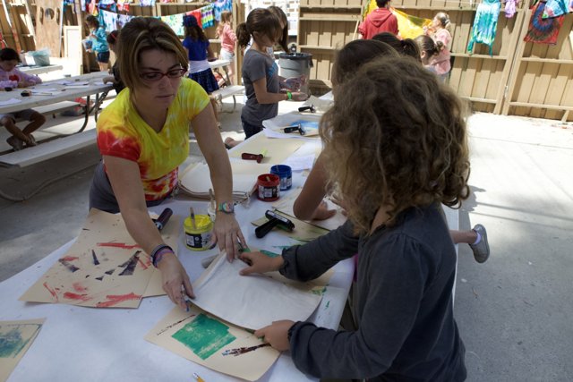 Crafting Memories Caption: A mother and her two daughters create their own artwork at a plywood table during the 2010 WBTLA camp.