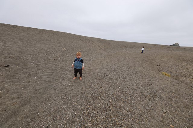 Toddler Smiling on Vast Gray Sand Dune