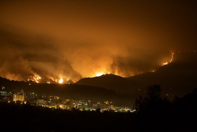 Scorching flames devour the night sky from atop a hill