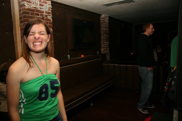 Woman in Green Jersey Laughing at Bar Party