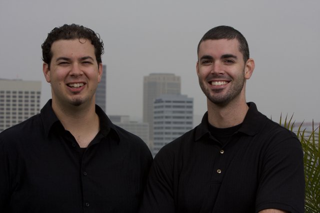 Two Happy Men in Black Shirts posing in front of a Skyscraper