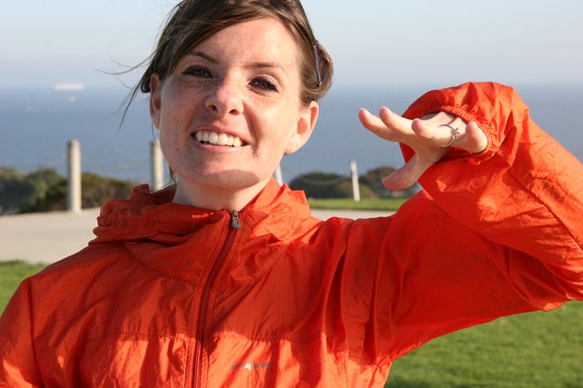 Smiling Woman in Orange Jacket by the Coast