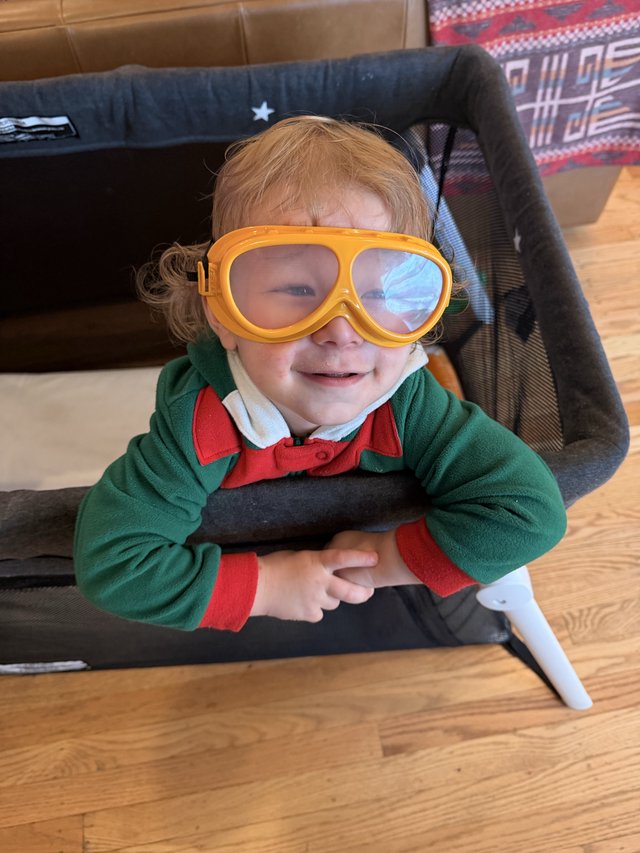 Joyful Toddler in Aviator Goggles and Green Sweater