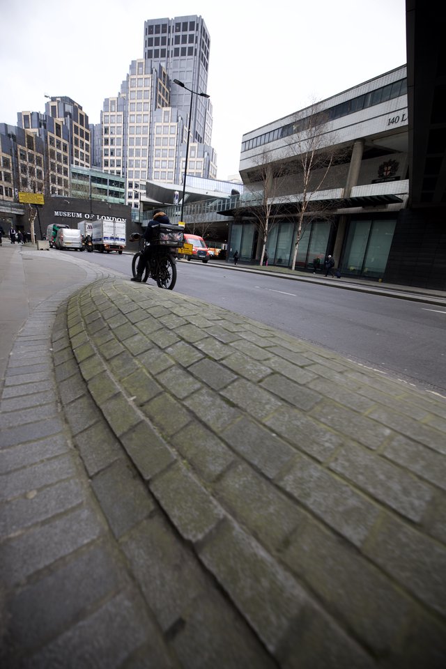 Motorcyclist Rides Past Museum of London in Urban Scene