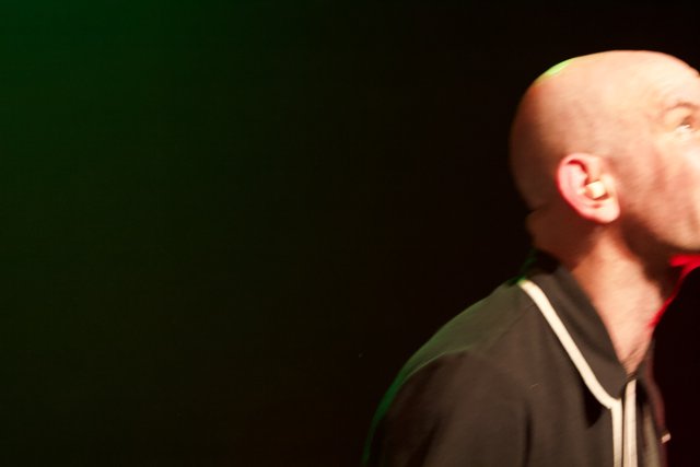 Bald man with microphone performs at the Glasshouse
