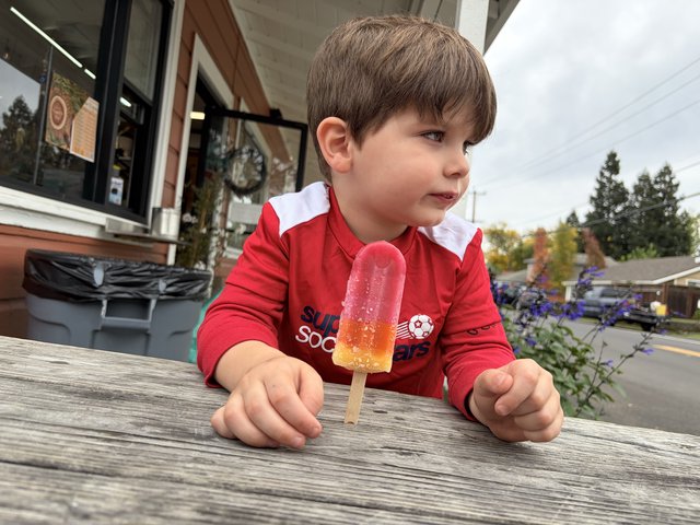 Young Boy Enjoying Colorful Popsicle on Outdoor Deck
