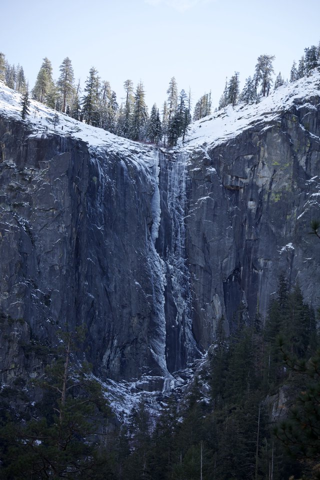 Frozen Waterfall Cascading Down Snow-Covered Basalt Cliffs
