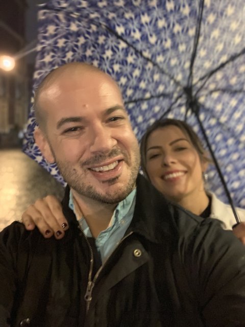Smiling Couple Captures Moment with Umbrella Selfie