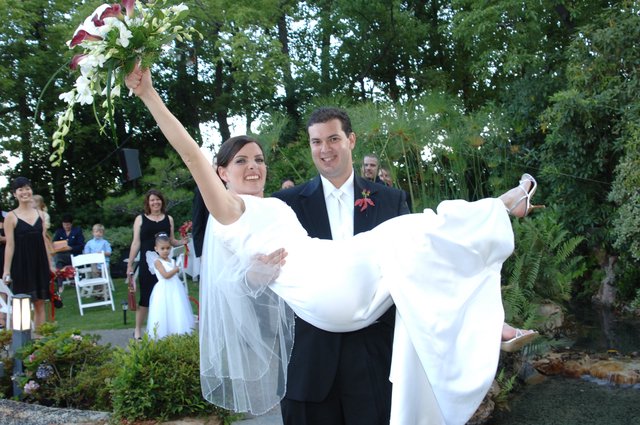 Groom Carries Jubilant Bride After Outdoor Garden Wedding