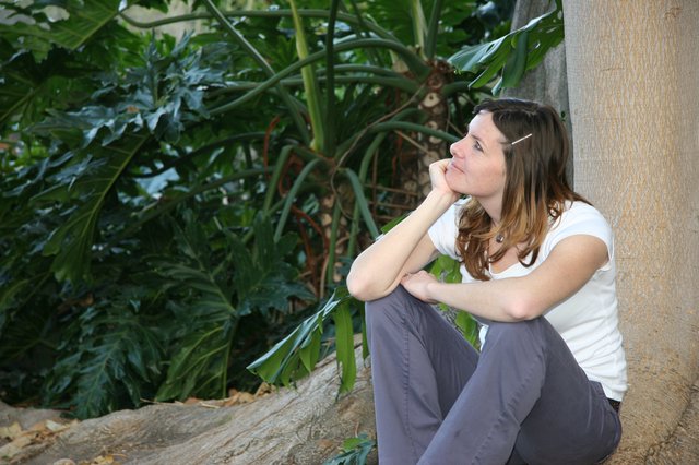 Contemplative Woman Resting Against Wall in Tropical Garden