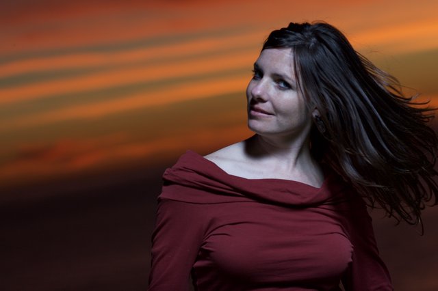 Woman in Red Beneath a Dramatic Sunset Sky