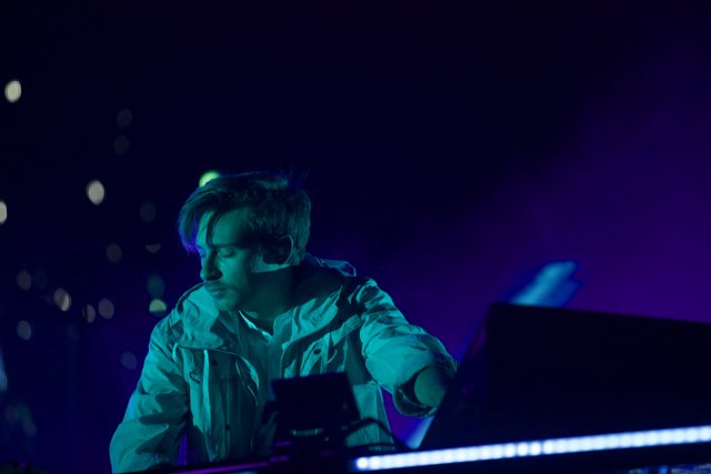 Flume in Concert Caption: Australian deejay Flume entertains the crowd at Coachella 2016, playing his keyboard and laptop while wearing a white jacket in the midst of an electric lighting and visual display on stage.