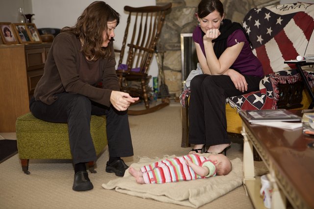 Two Women Admiring a Newborn Baby on Floor