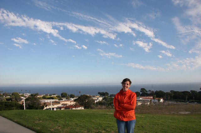 Woman in Orange Jacket Overlooking Coastal Town