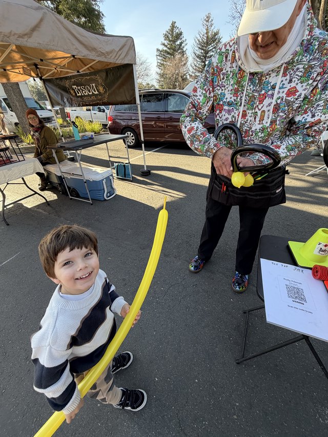 Young Boy Enjoys Balloon Sword at Community Market Event