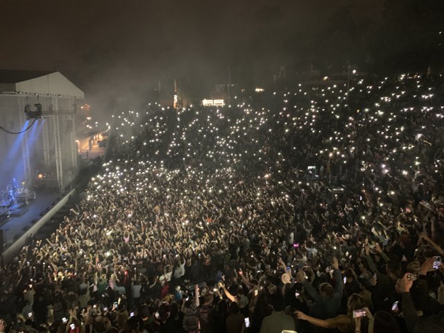 Phone-lit Crowd Rocks Out under Night Sky