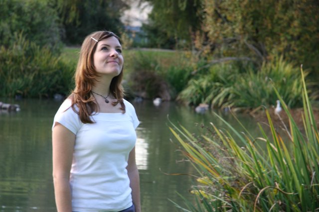 Young Woman Gazing Upward by a Tranquil Pond