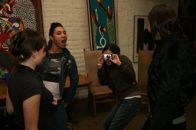 Friends Laughing and Photographing at Indoor Gathering
