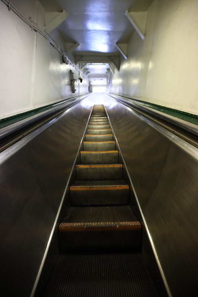 Ascending the Steep Escalator into Illuminated Transit Tunnel