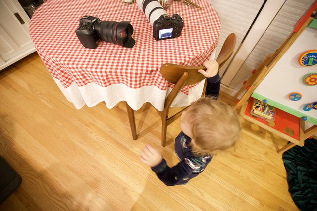 Young Child Reaching Toward Camera Equipment on Table