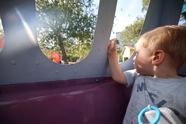 Young Child Gazing Through Playground Window at Park
