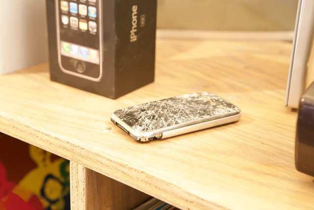 Broken iPhone Resting on Wooden Table